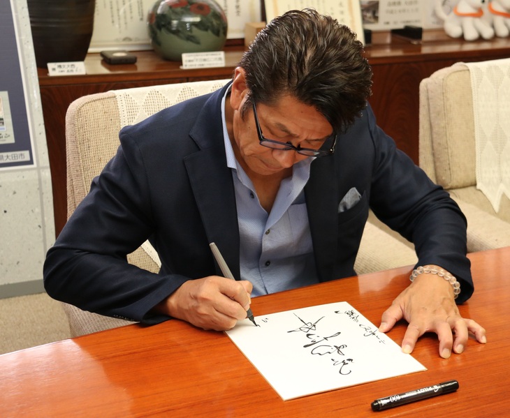 野村さんがサインを書いているところ