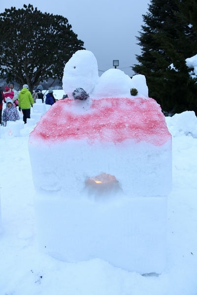 雪でできたスヌーピーが上に乗った家