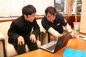 高田さんが楫さんにプログラミングの指導をしているようす
