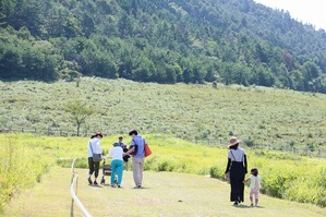 押し車を押すおばあさんの手を取りながら歩く家族