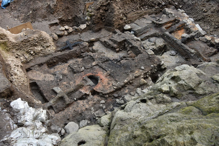 石の列で区画された中に赤く焼けた製錬炉の痕跡が見つかった発掘現場の写真