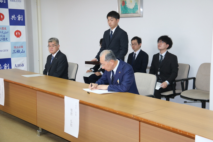 協定書にサインする市長