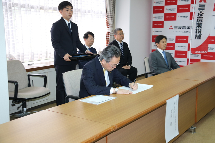 協定書にサインする齋藤CEO取締役社長
