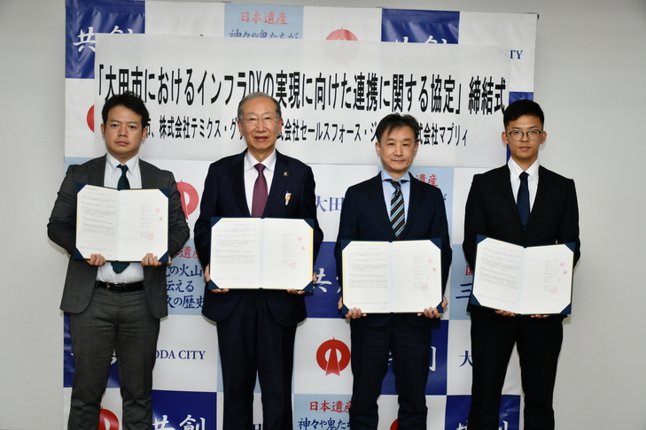 資料と３社の代表者の集合写真