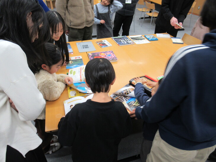 おえかき前資料本を見る子ら