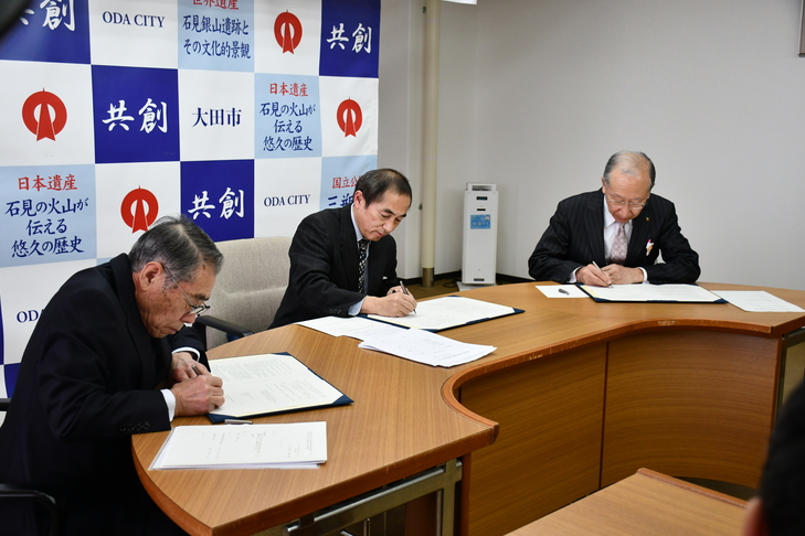 三者がサインするシーン