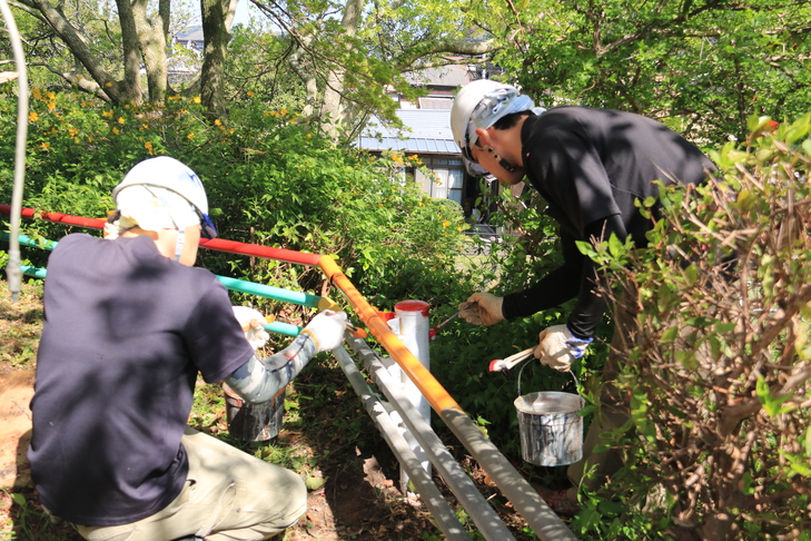 ペンキで外周柵を塗る組合員