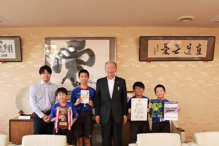 市長と選手4人と監督の集合写真