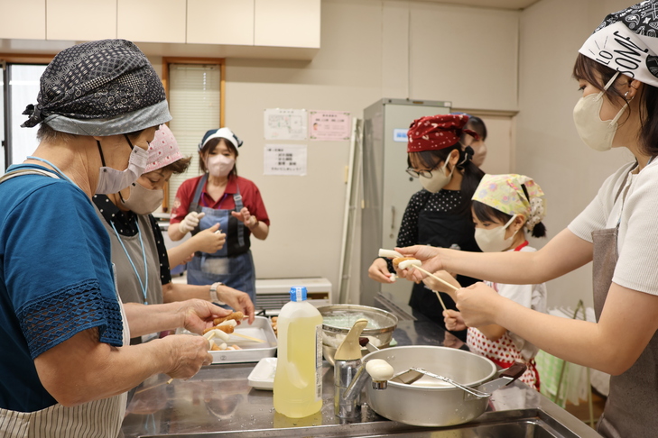 串にソーセージとお餅を刺す参加者