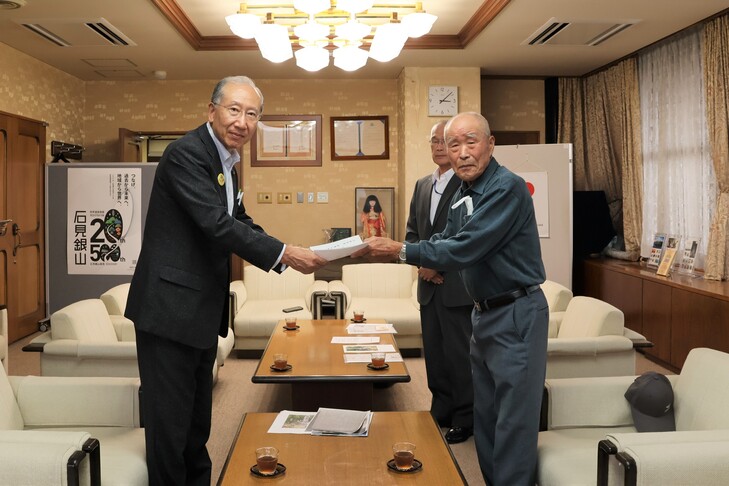 寄付金を渡す山下さんと受け取る市長
